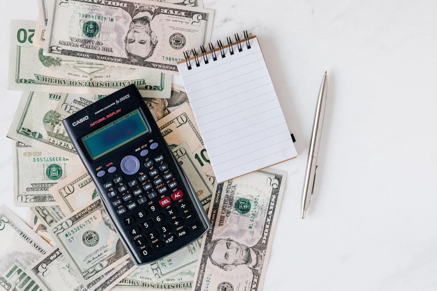 Calculator, notebook and US dollar bills used to plan a budget