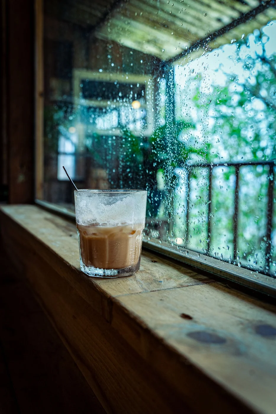 A coffee drink indoors beside a rain-speckled window