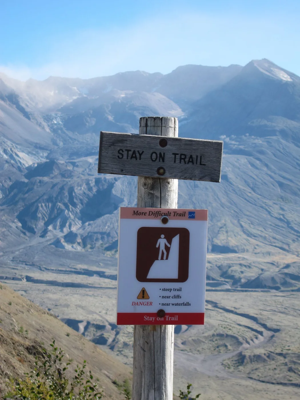 A trail warning sign asking visitors to remain on the marked route