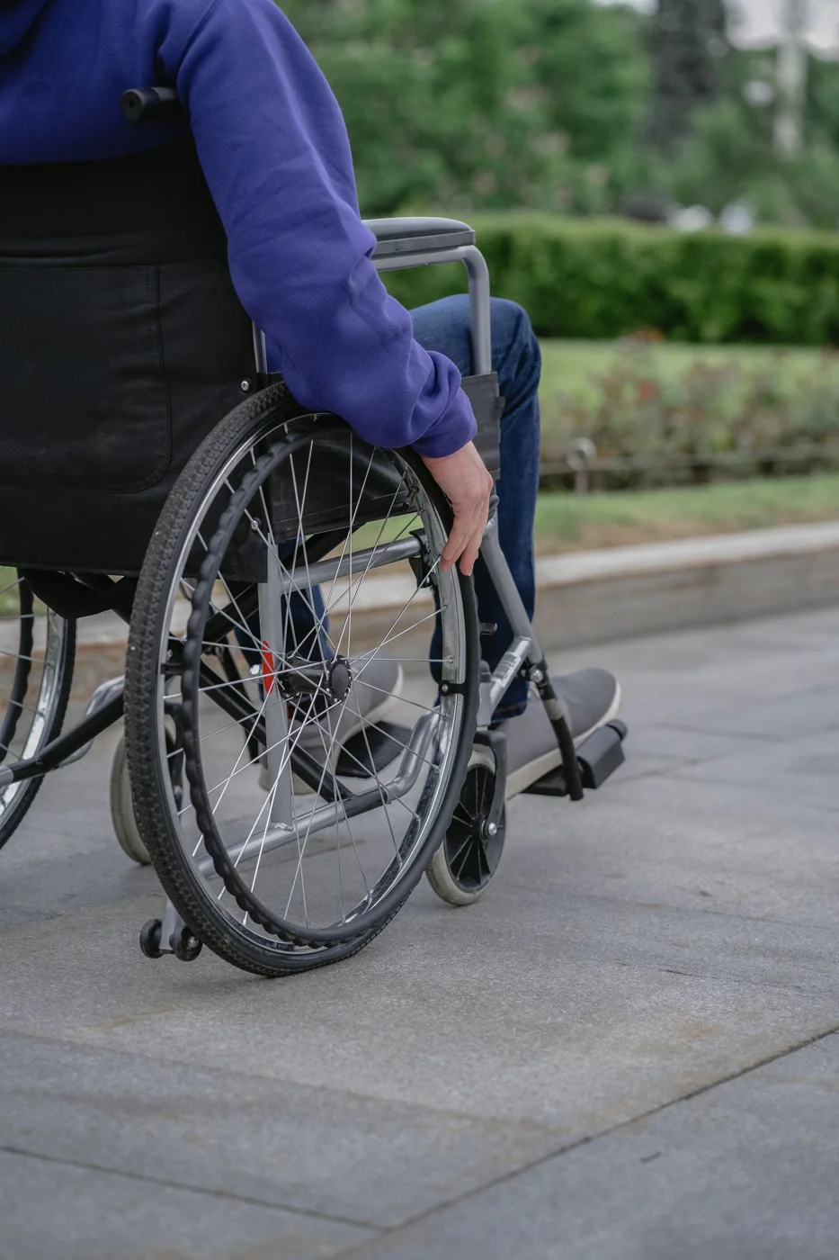 A wheelchair user travelling along a paved outdoor walkway